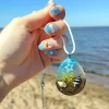 Merellinen käsintehty pisarariipus aidolla hiekalla ja simpukoilla